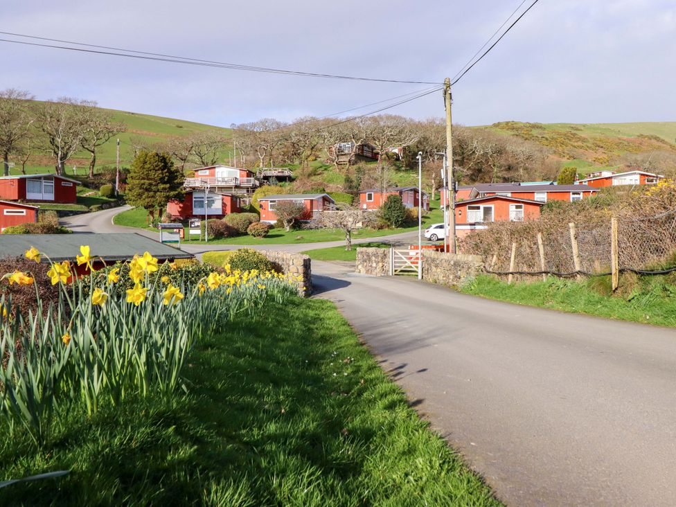 A view of red huts and a road with yellow flowers at Chalet 23 Erw Porthor Tywyn