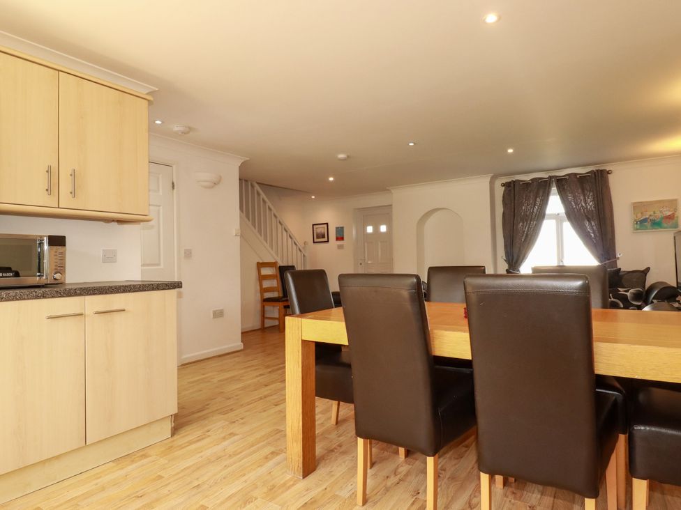 A dining room with a kitchen unit and dining table at 62 Golf Lodges, Atlantic Reach near Fraddon