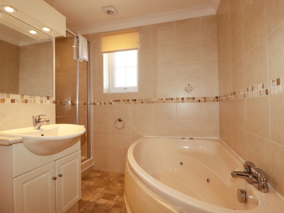 A bathroom with a bathtub, shower, sink, and mirror at 62 Golf Lodges in Atlantic Reach near Fraddon