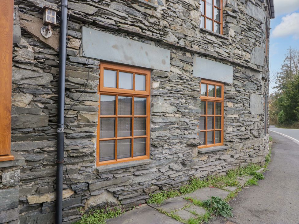 A stone wall with windows and grass at Wilders Wood, Windermere