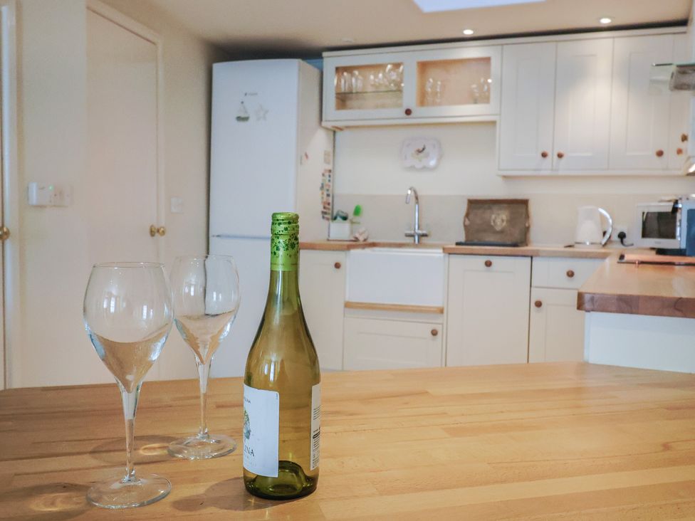 A kitchen with wine glasses and a bottle on the countertop at Phoenix Cottage in Lyme Regis