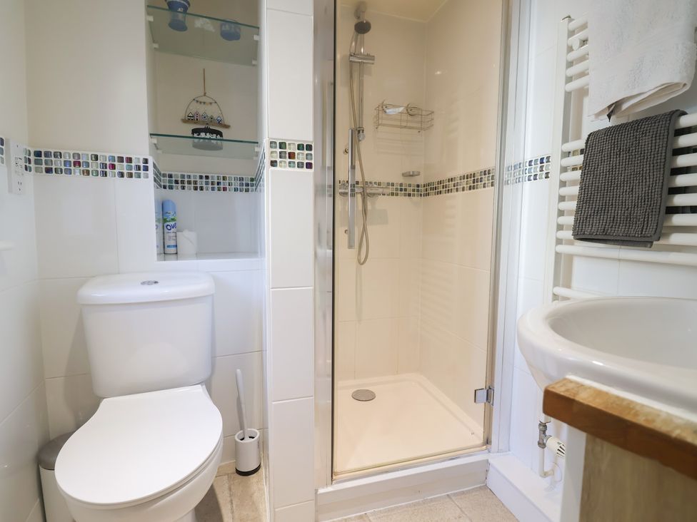 A bathroom with a shower, toilet, and sink at Phoenix Cottage Lyme Regis