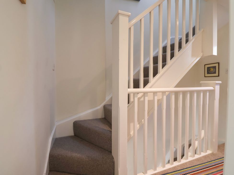 A staircase with a handrail and carpet in Phoenix Cottage Lyme Regis