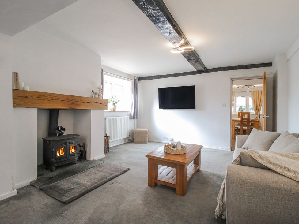 A living room with a fireplace and television at Corner House in Minsterley