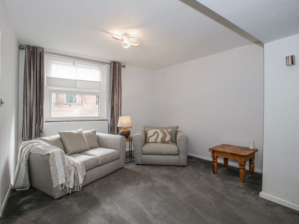A living room with a sofa, lamp, and side table at Corner House in Minsterley