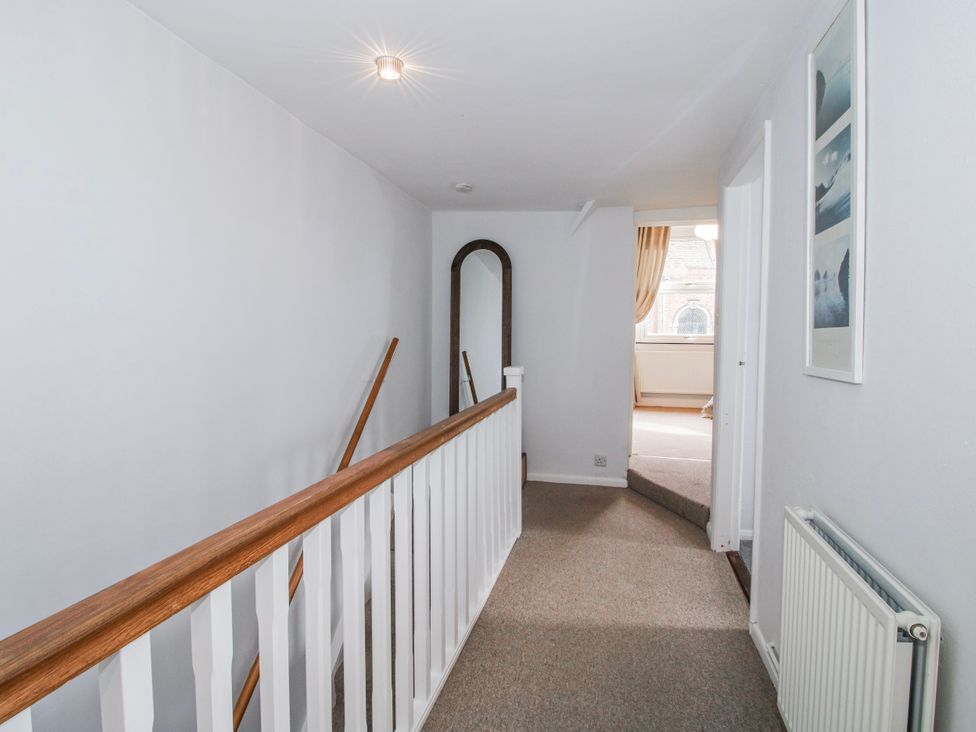 A hallway with a stair railing and a mirror at Corner House in Minsterley