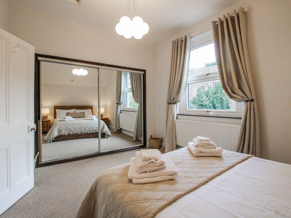 A bedroom with a bed and mirror at Corner House in Minsterley