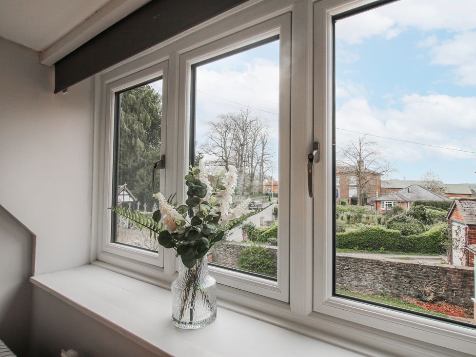 A window with flowers in a vase overlooking a road at Corner House Minsterley