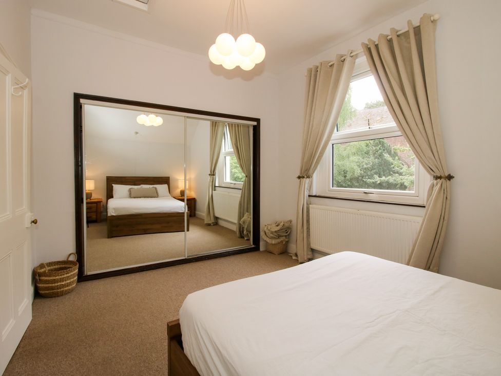 A bedroom with a bed and mirror at Corner House in Minsterley