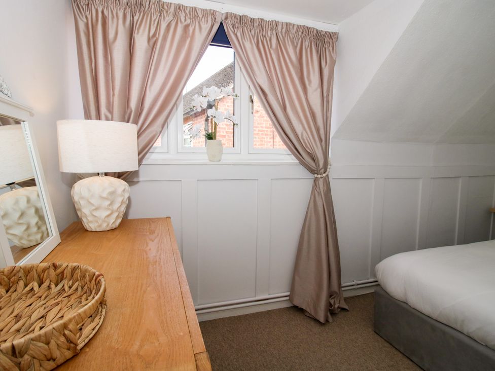 A bedroom with a window, curtains, and a dresser at Corner House, Minsterley