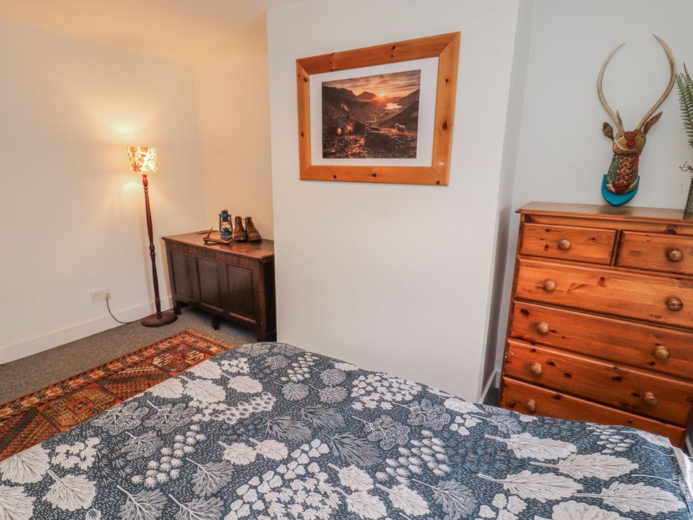 A bedroom with a bed, lamp, and wooden furniture at 25 Low Seaton in Workington