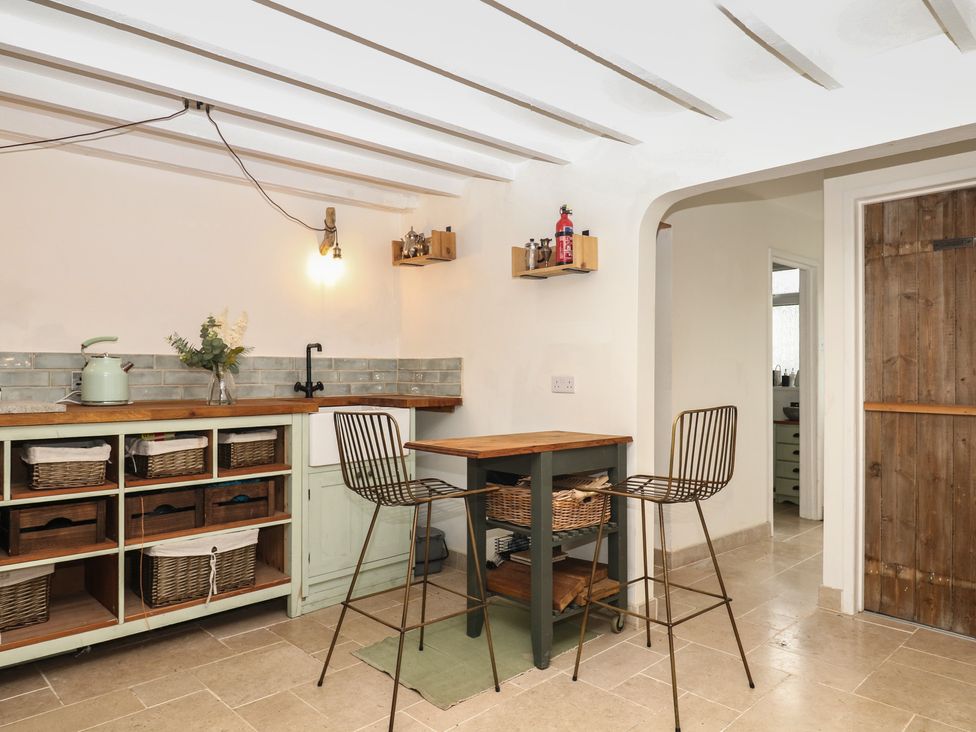 A kitchen with a counter and bar stools at Bedford Cottage in Yelverton