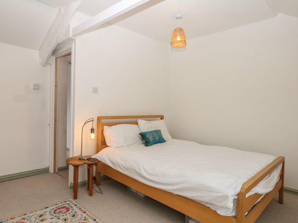 A bedroom with a bed and side table at Bedford Cottage in Yelverton