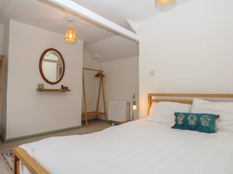 A bedroom with a bed and mirror at Bedford Cottage in Yelverton