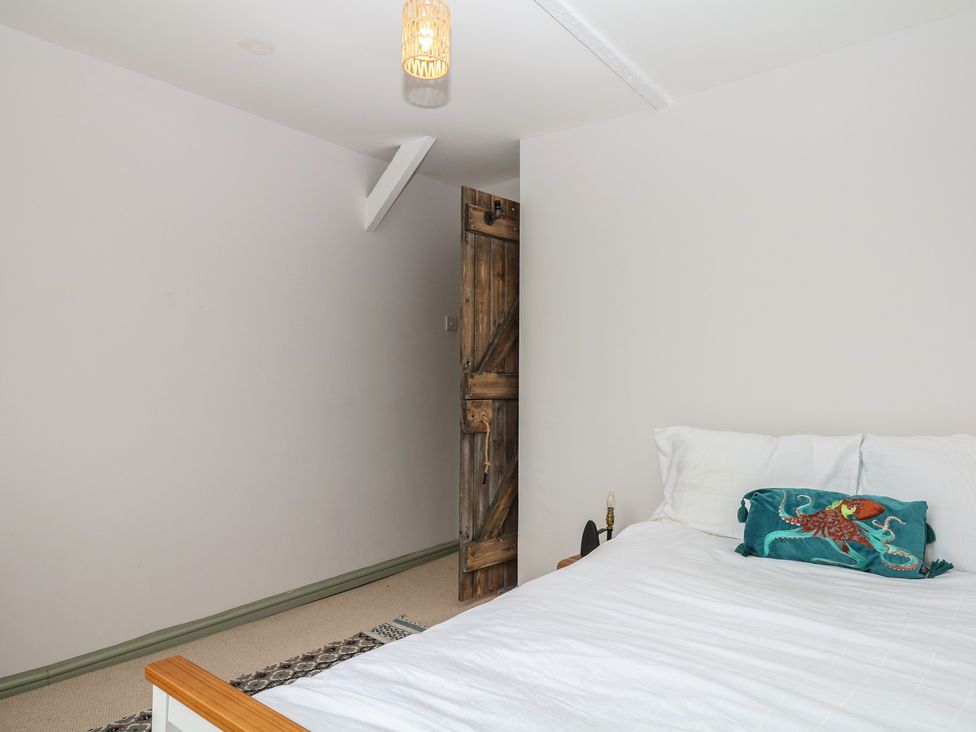 A bedroom with a bed and a wooden door at Bedford Cottage Yelverton