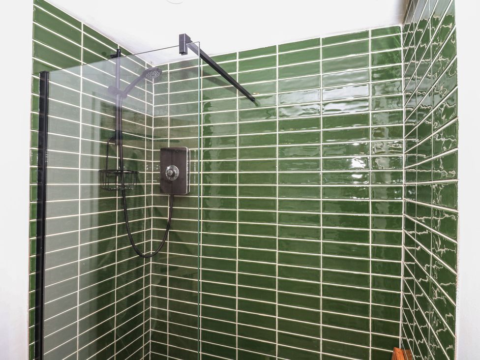 A shower with green tiles at Bedford Cottage in Yelverton