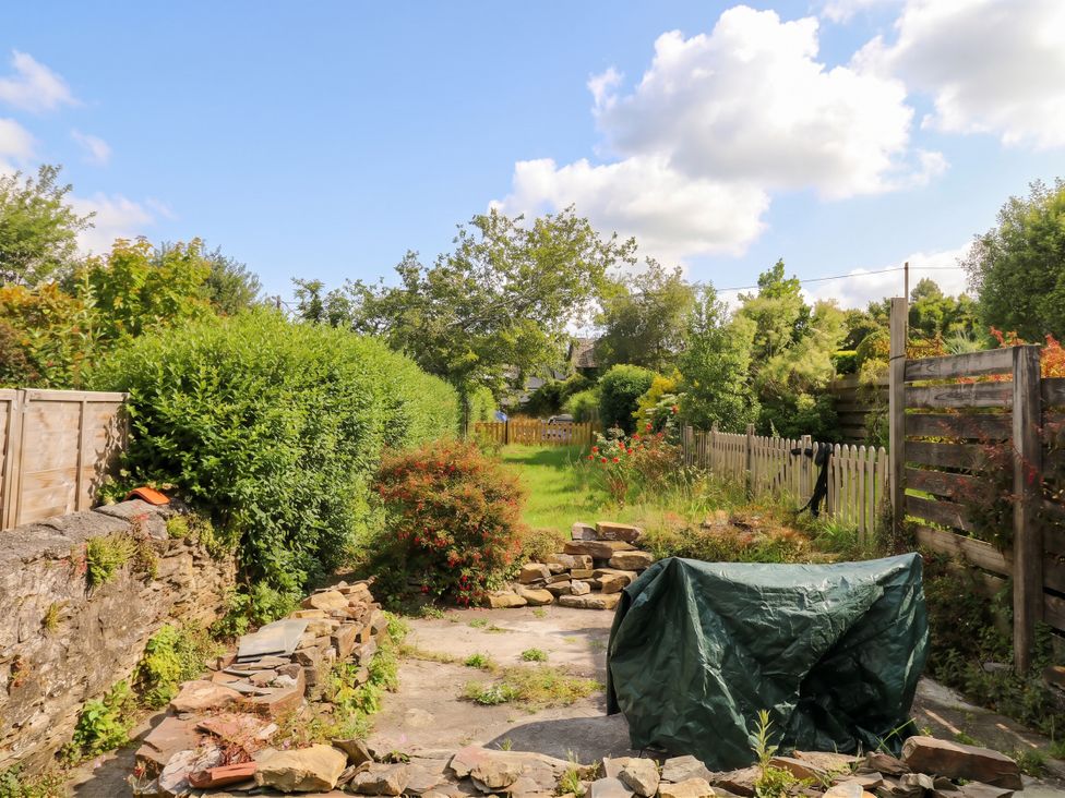A garden with a stone patio and hedges at Bedford Cottage in Yelverton