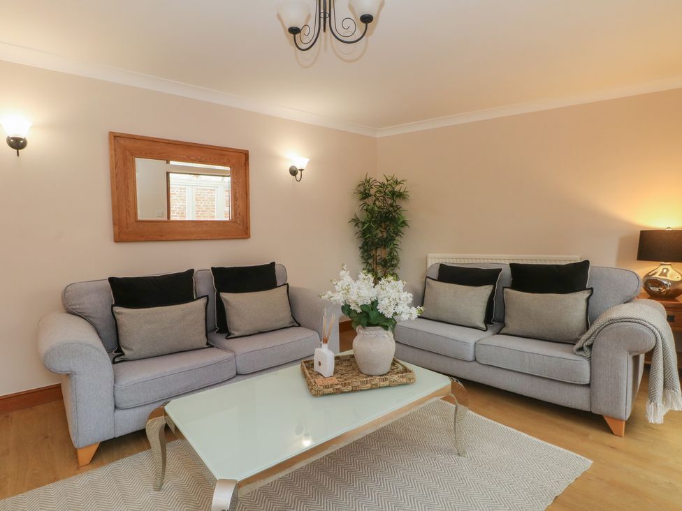 A living room with sofas and a glass table at 1 The Stables Wrexham
