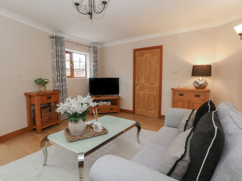 A living room with a sofa, coffee table, and television at 1 The Stables Wrexham