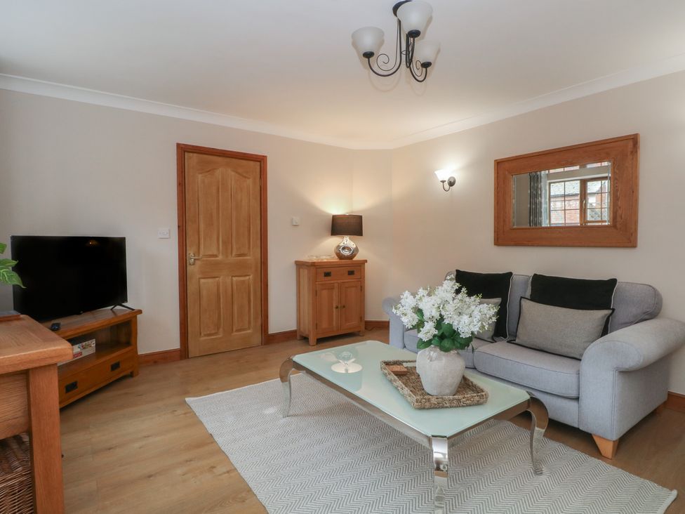A living room with a sofa, table, and television at 1 The Stables Wrexham