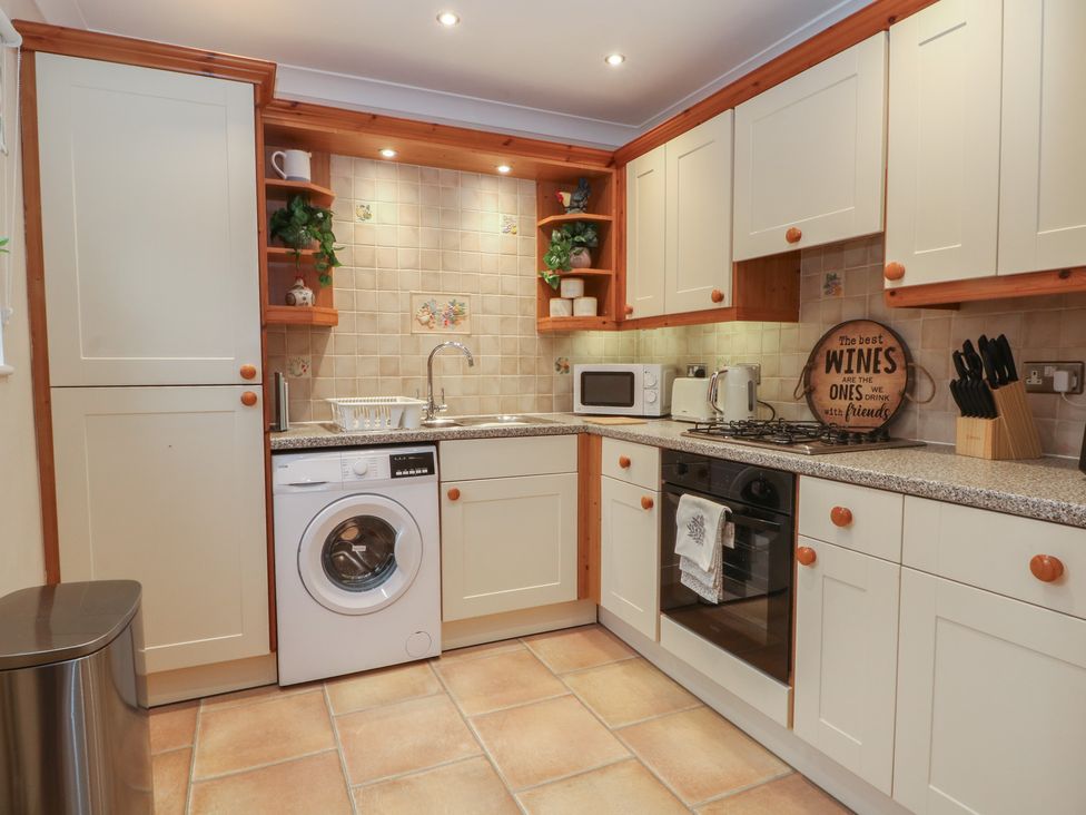 A kitchen with cabinets, sink, microwave, washing machine, and oven at 1 The Stables Wrexham