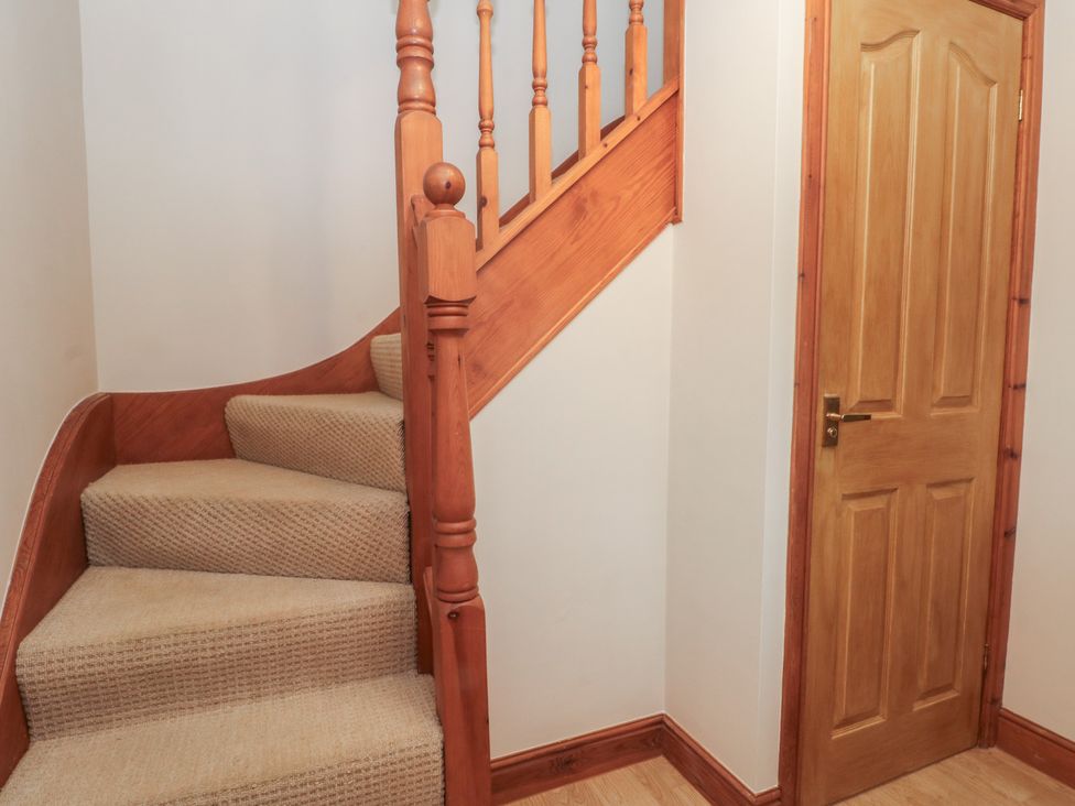 A staircase with a wooden railing and a door in a hallway at 1 The Stables Wrexham