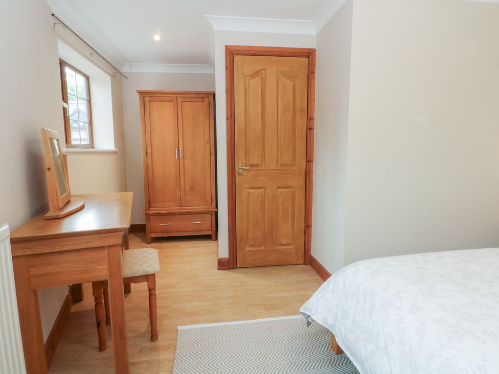 A bedroom with a wardrobe, desk, and chair at 1 The Stables in Wrexham