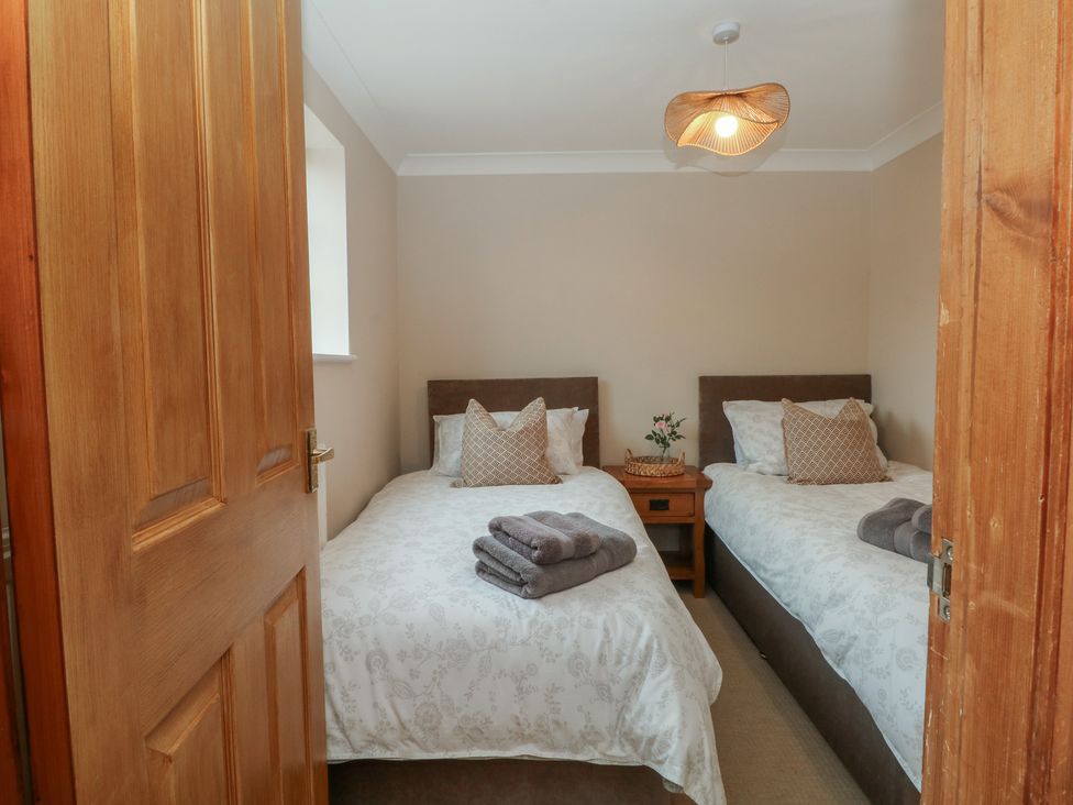 A bedroom with two beds and a bedside table at 1 The Stables Wrexham