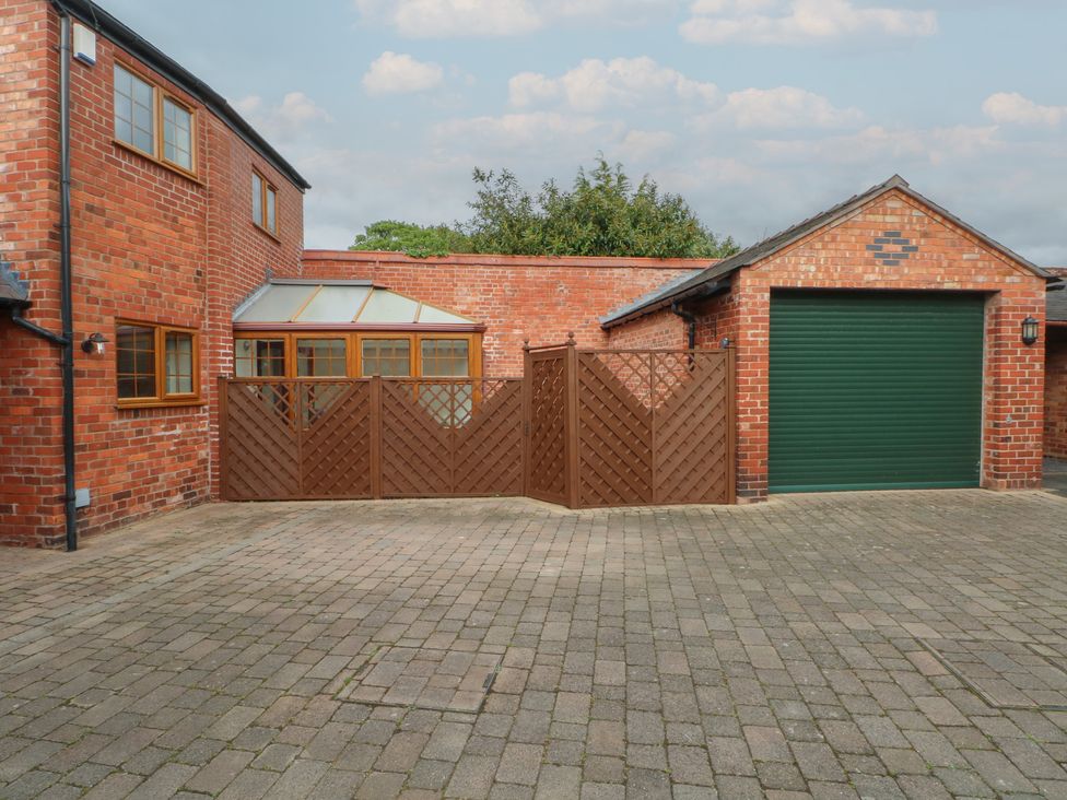 An exterior view with a garage and a fenced area at 1 The Stables Wrexham