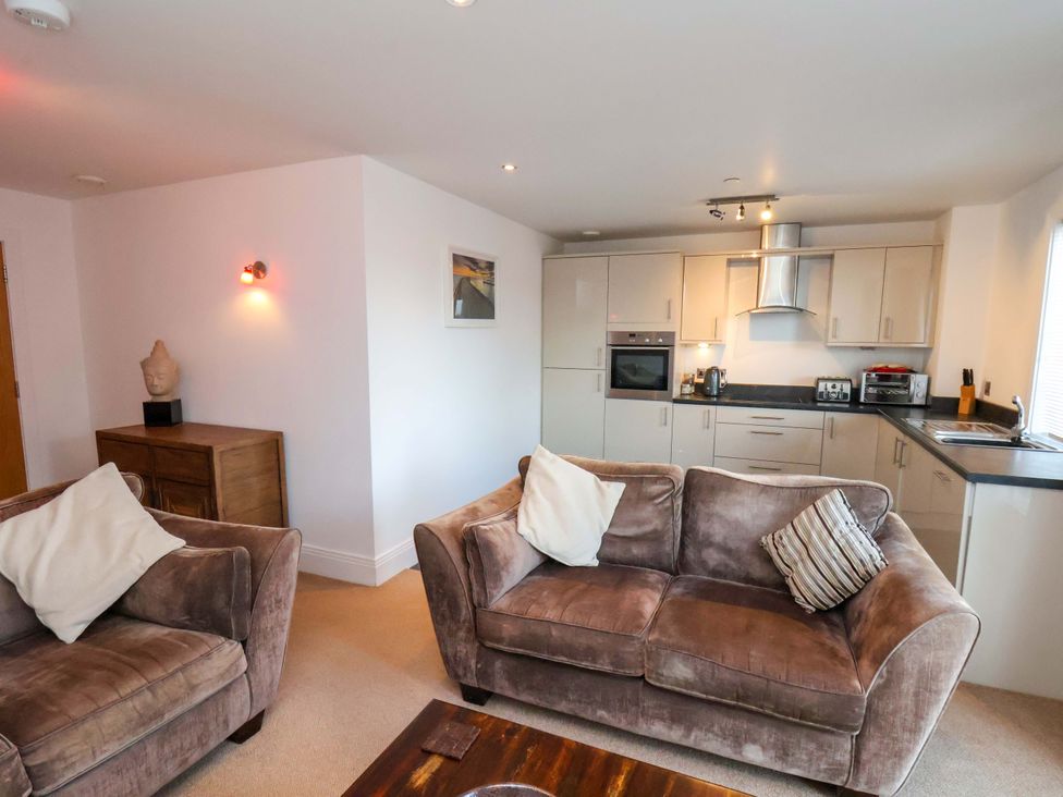 A living room with a sofa and kitchen units at Apartment 12