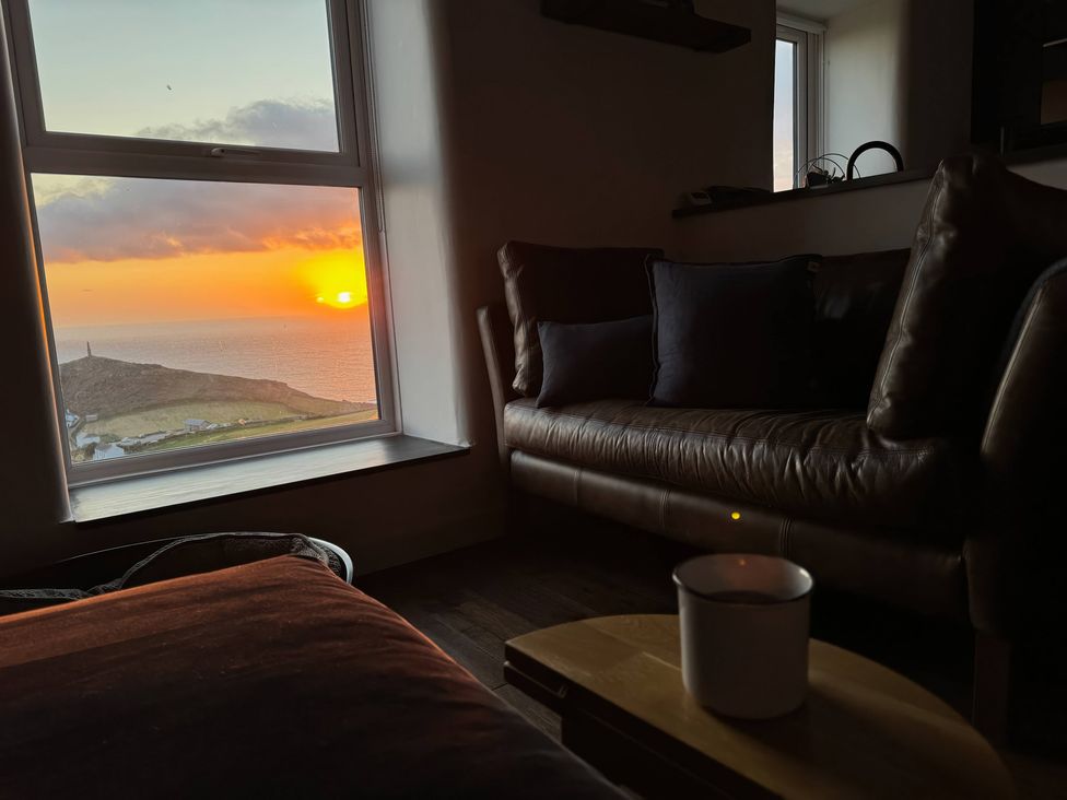 A living room with a couch and sunset view at Cape View in Cape Cornwall near St Just