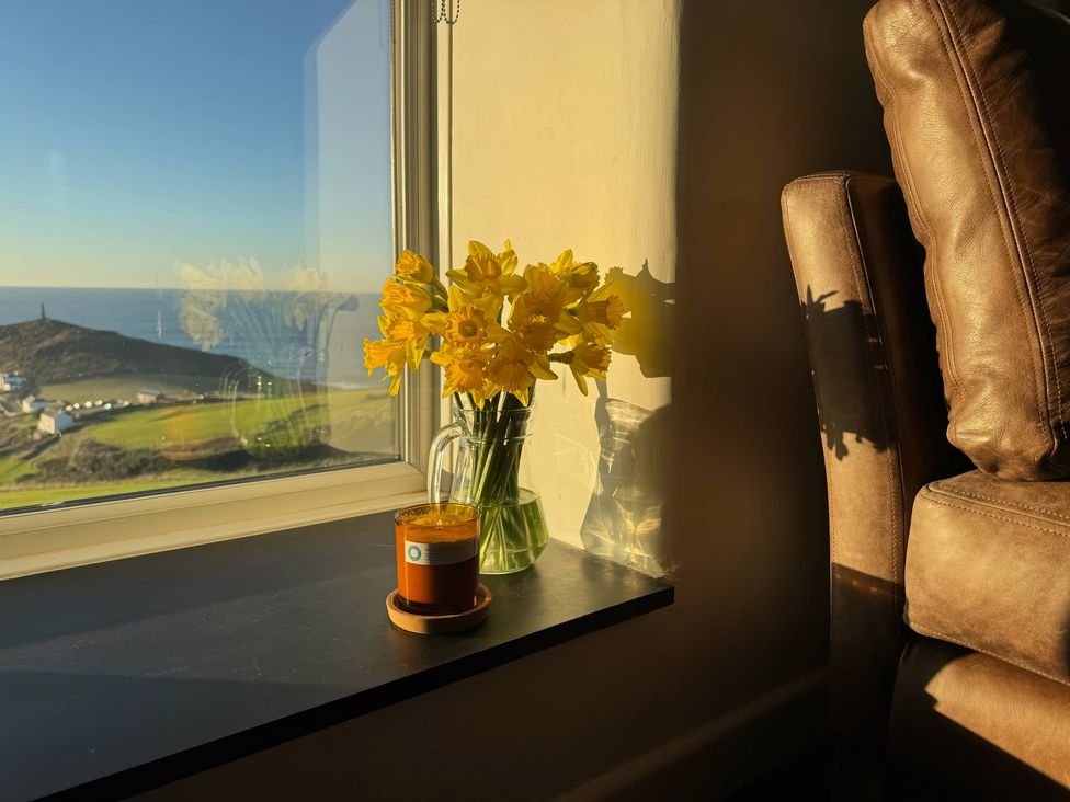 A living room with flowers and a coffee cup at Cape View Cape Cornwall near St Just