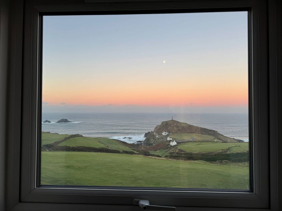 A view of ocean and hill with a lighthouse at Cape View in Cape Cornwall near St Just