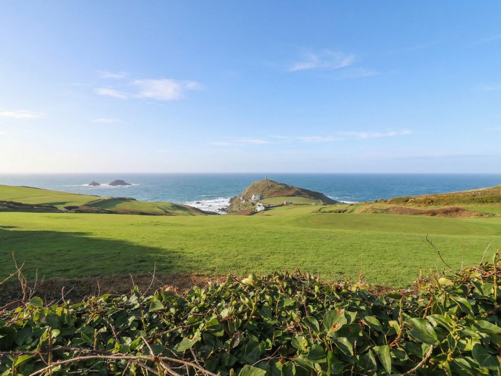 A view of a hill and lighthouse by the ocean at Cape View in Cape Cornwall near St Just