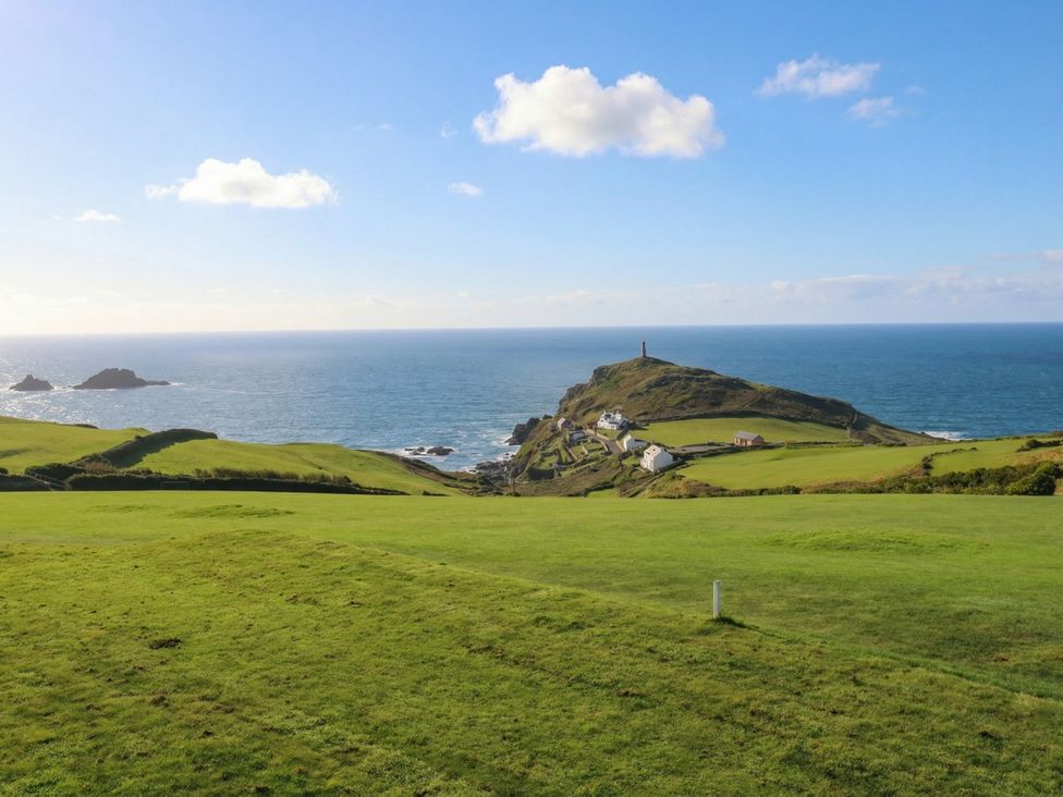 A coastal view with green fields and a lighthouse at Cape View in Cape Cornwall near St Just