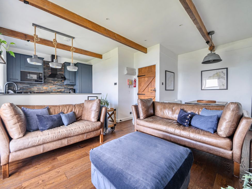 A living room with sofas and a kitchen area at Cape View near St Just