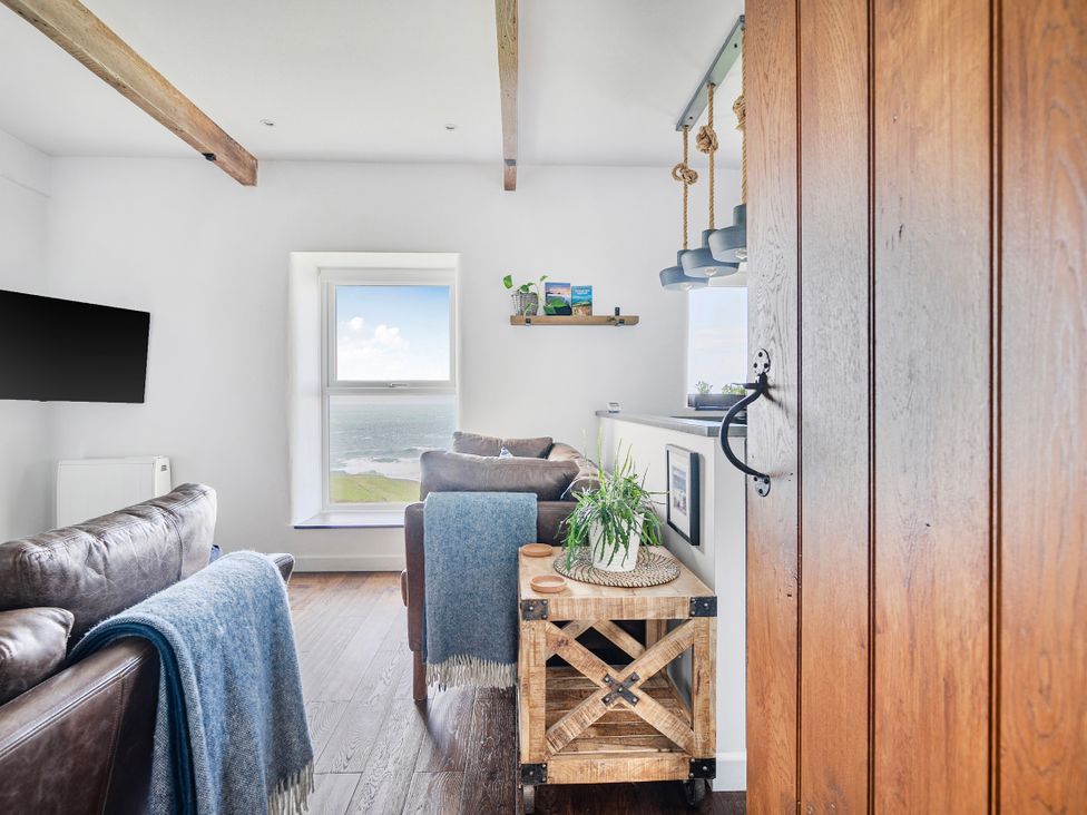 A living room with a sofa and window view at Cape View Cape Cornwall near St Just