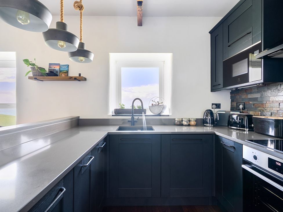 A kitchen with a sink, cabinets, and appliances at Cape View near St Just