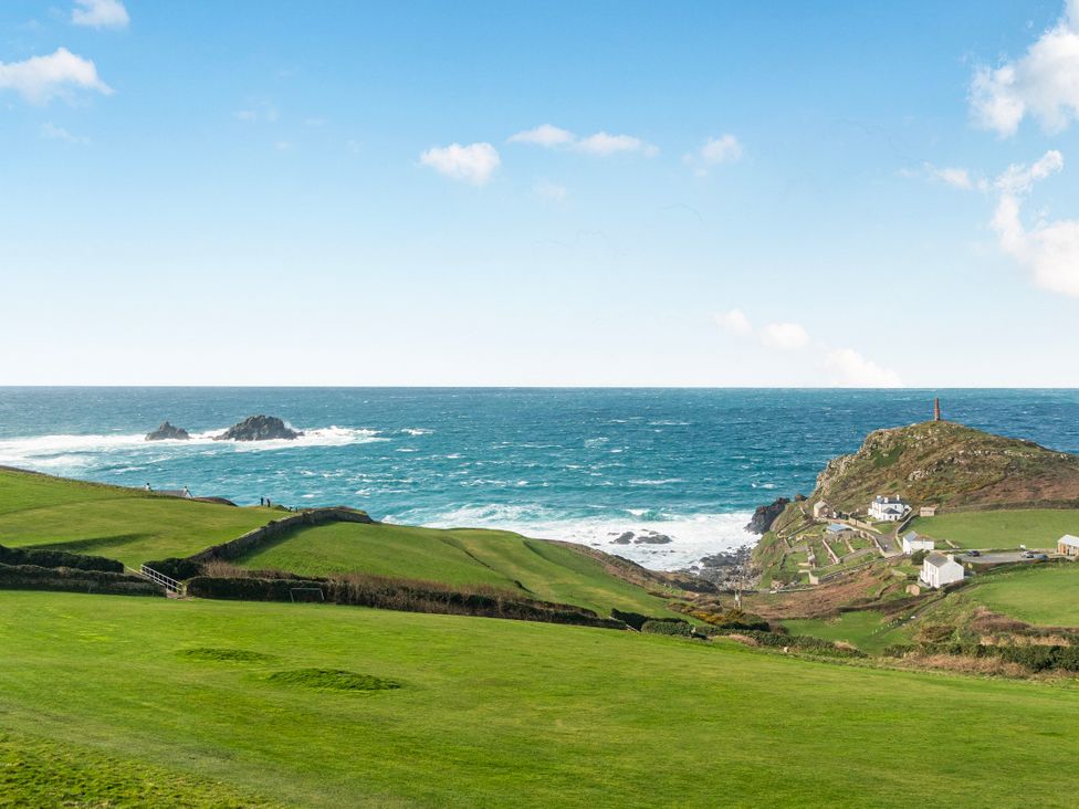 A view of the ocean and cliff with houses and a lighthouse at Cape View near Cape Cornwall