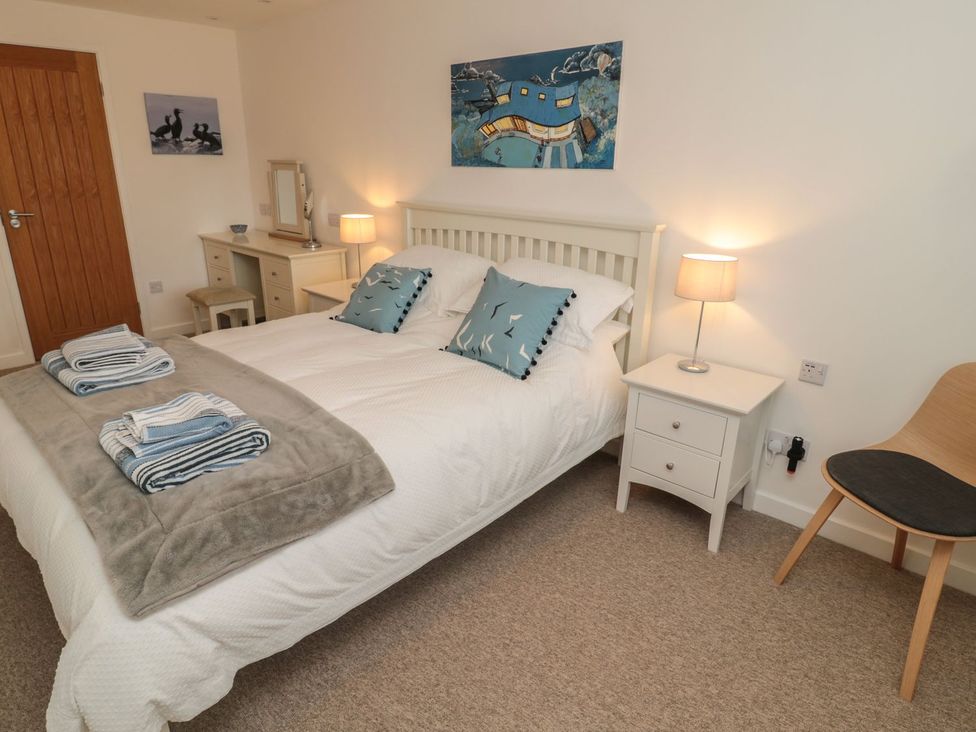 A bedroom with a bed, chair, and lamp at 7 Longstone Close in Chathill