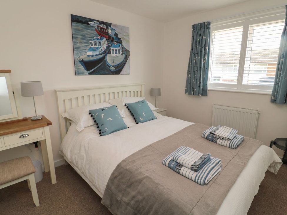 A bedroom with a bed, table, and artwork at 7 Longstone Close in Chathill