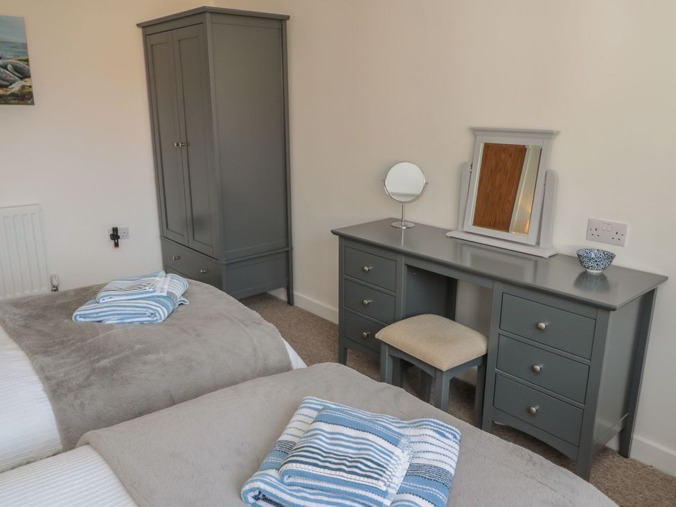 A bedroom with two beds and a dressing table at 7 Longstone Close Chathill