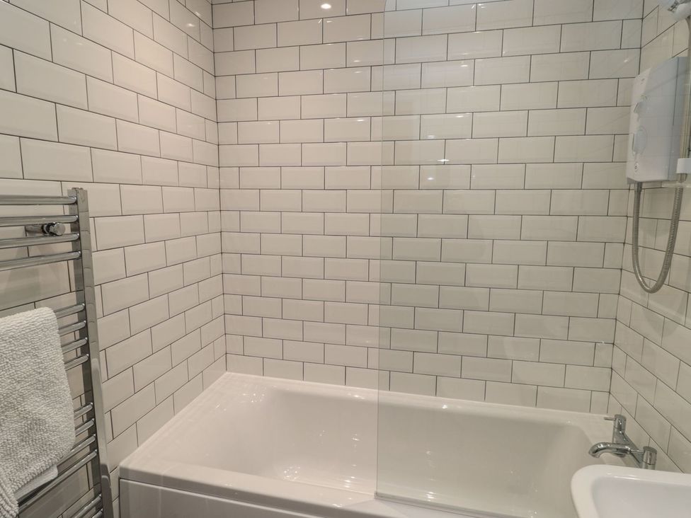 A bathroom with a bathtub and shower at 7 Longstone Close in Chathill