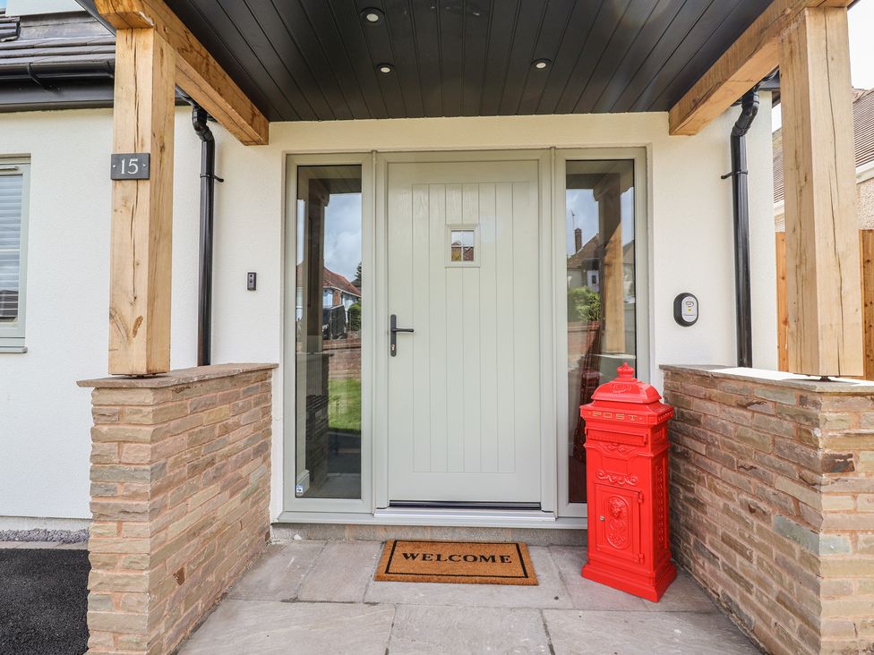 A front entrance with a door, welcome mat and a red post box at Bella Vista in Deganwy