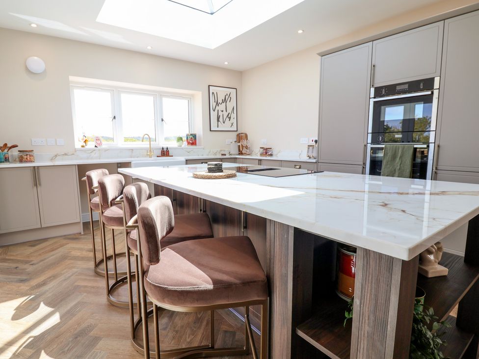 A kitchen with an island and bar stools at Bella Vista in Deganwy