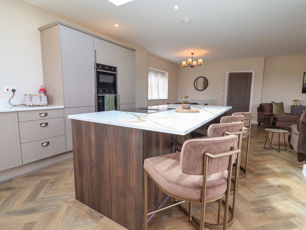 A kitchen with an island and bar stools at Bella Vista in Deganwy