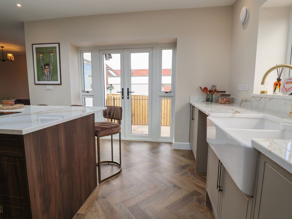 A kitchen with a bar stool and sink at Bella Vista in Deganwy