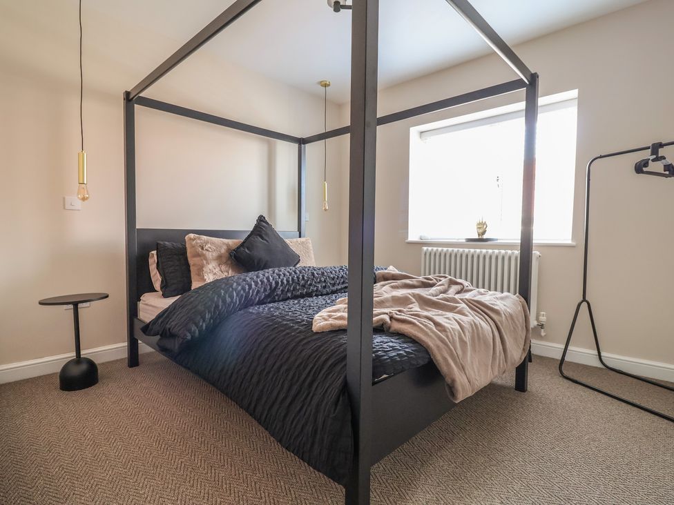A bedroom with a four-poster bed and window at Bella Vista Deganwy