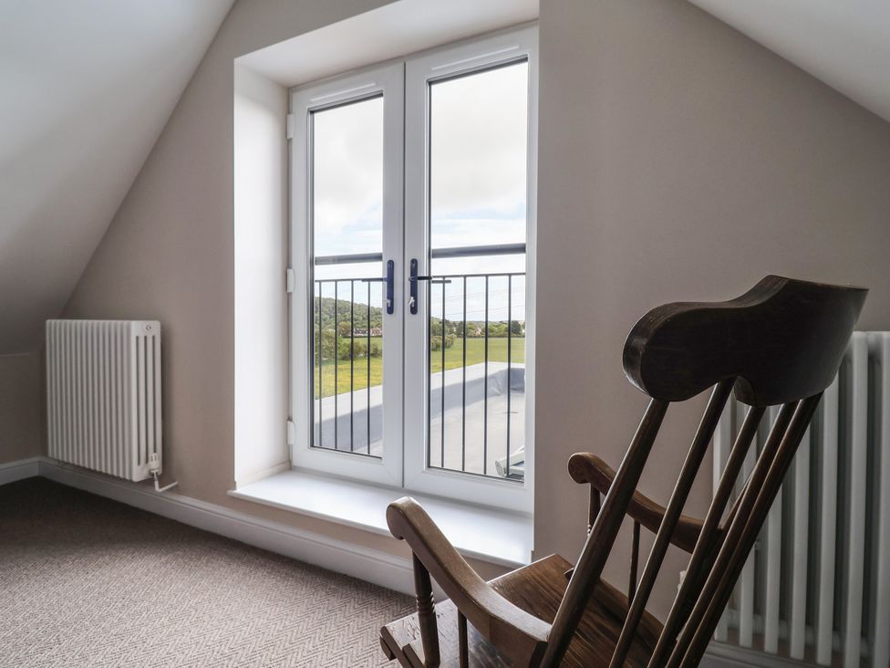 An attic with a rocking chair and a window at Bella Vista in Deganwy