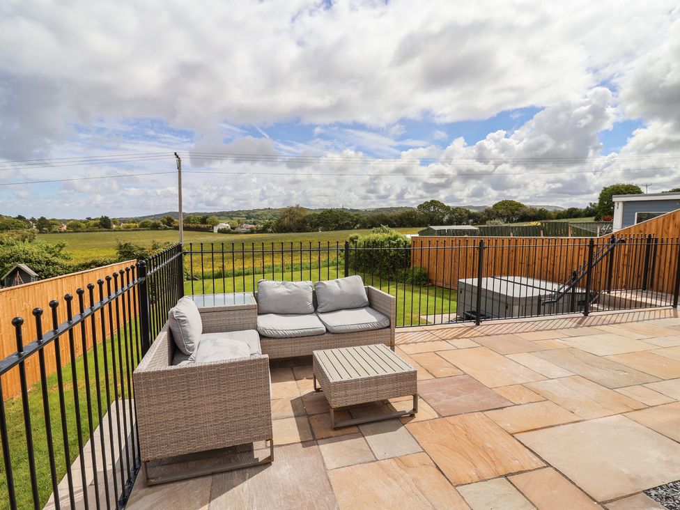 An outdoor area with a sofa and table overlooking fields at Bella Vista in Deganwy